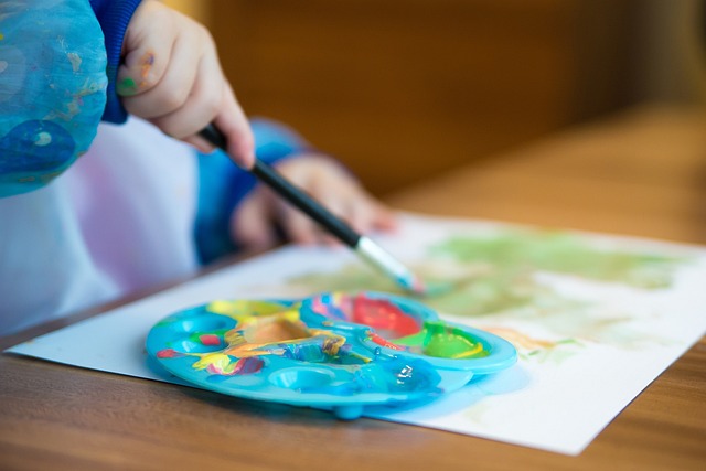Mano de niño pintando con pincel y acuarelas